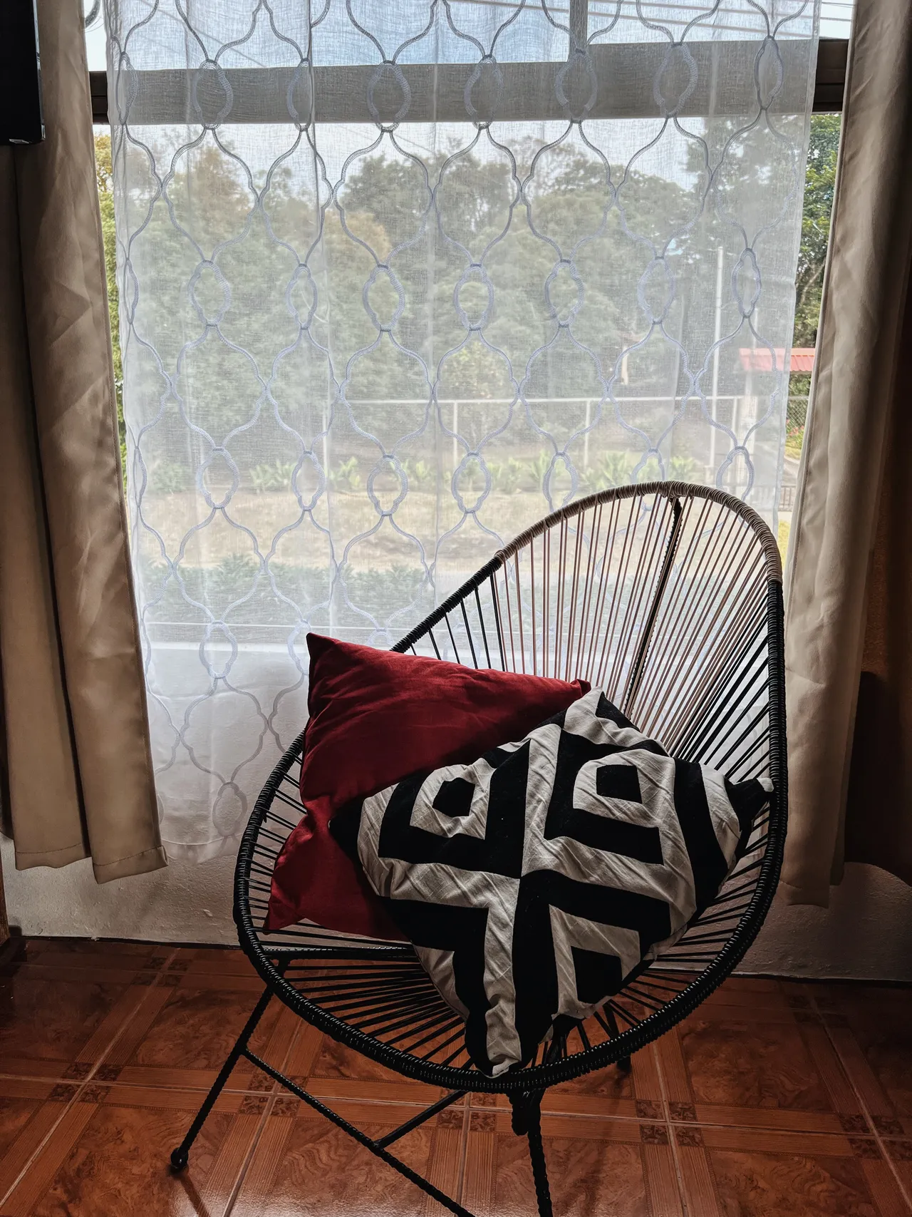 Silla acapulco con cojines junto a la ventana