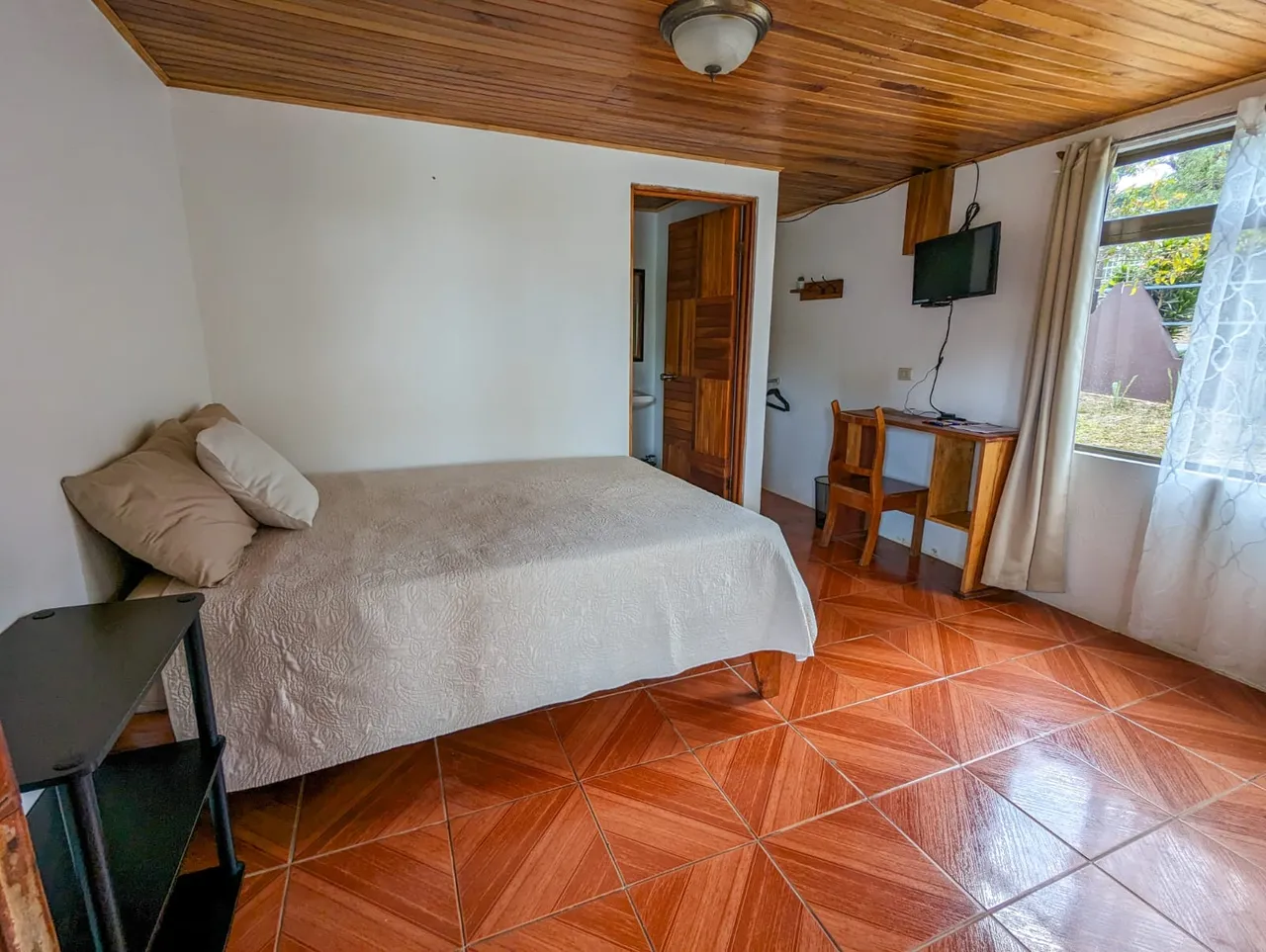 Habitación con cama matrimonial, televisor y ventana