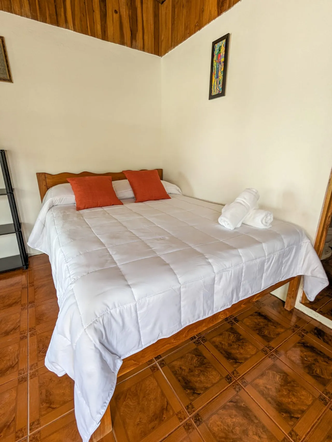 Cama matrimonial con sábanas blancas y almohadas naranjas