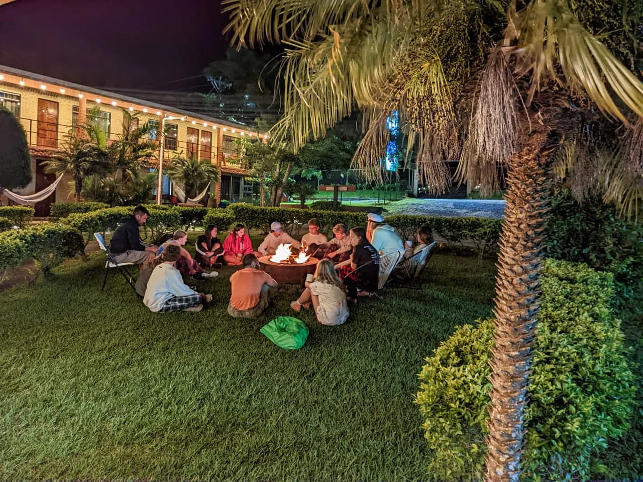 Huéspedes reunidos alrededor de la fogata en el jardín de noche