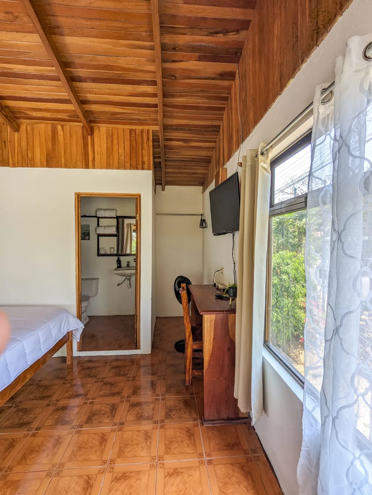 Habitación con escritorio, televisor y ventanal