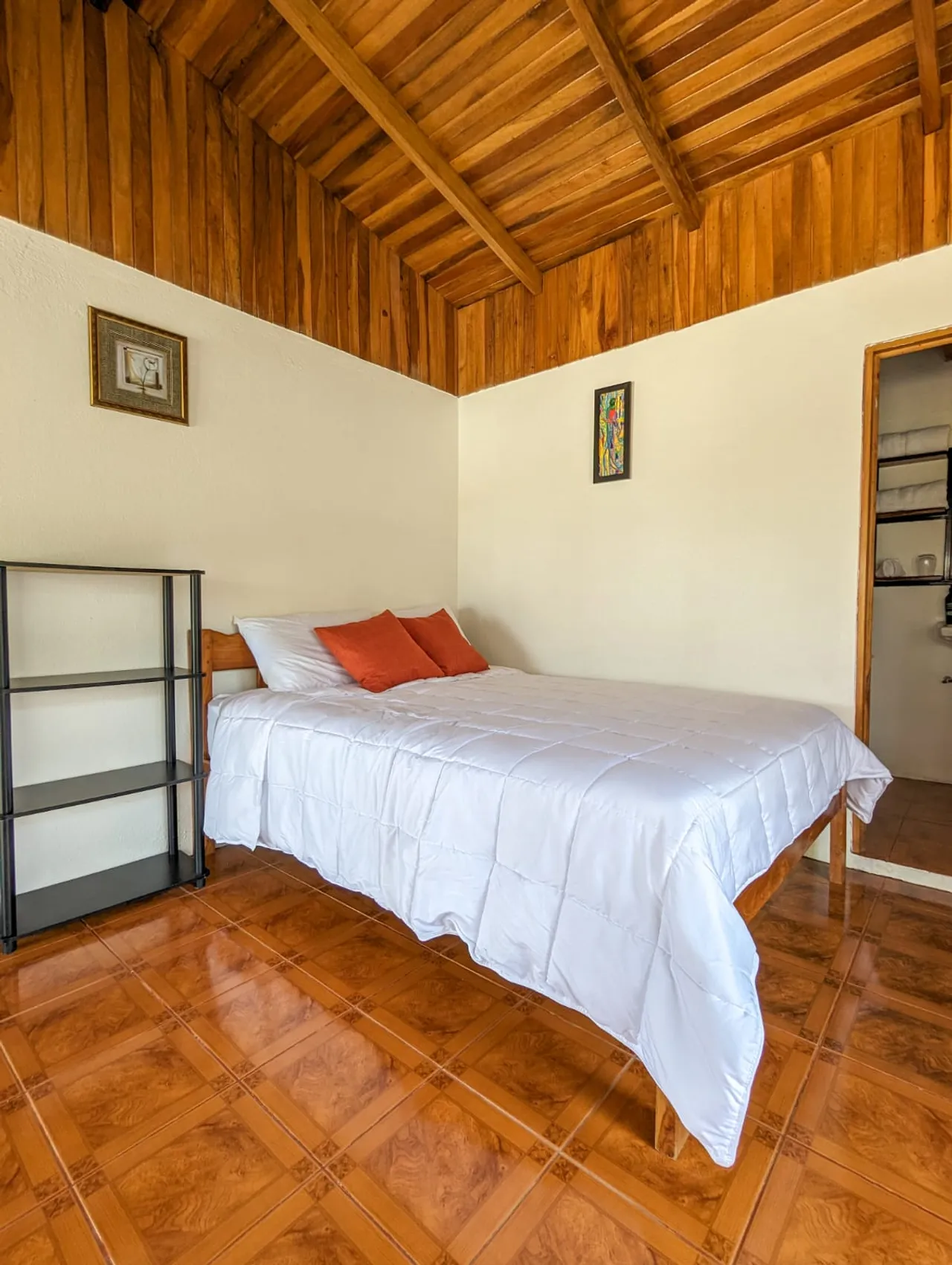 Habitación con cama matrimonial, techo de madera y baño privado