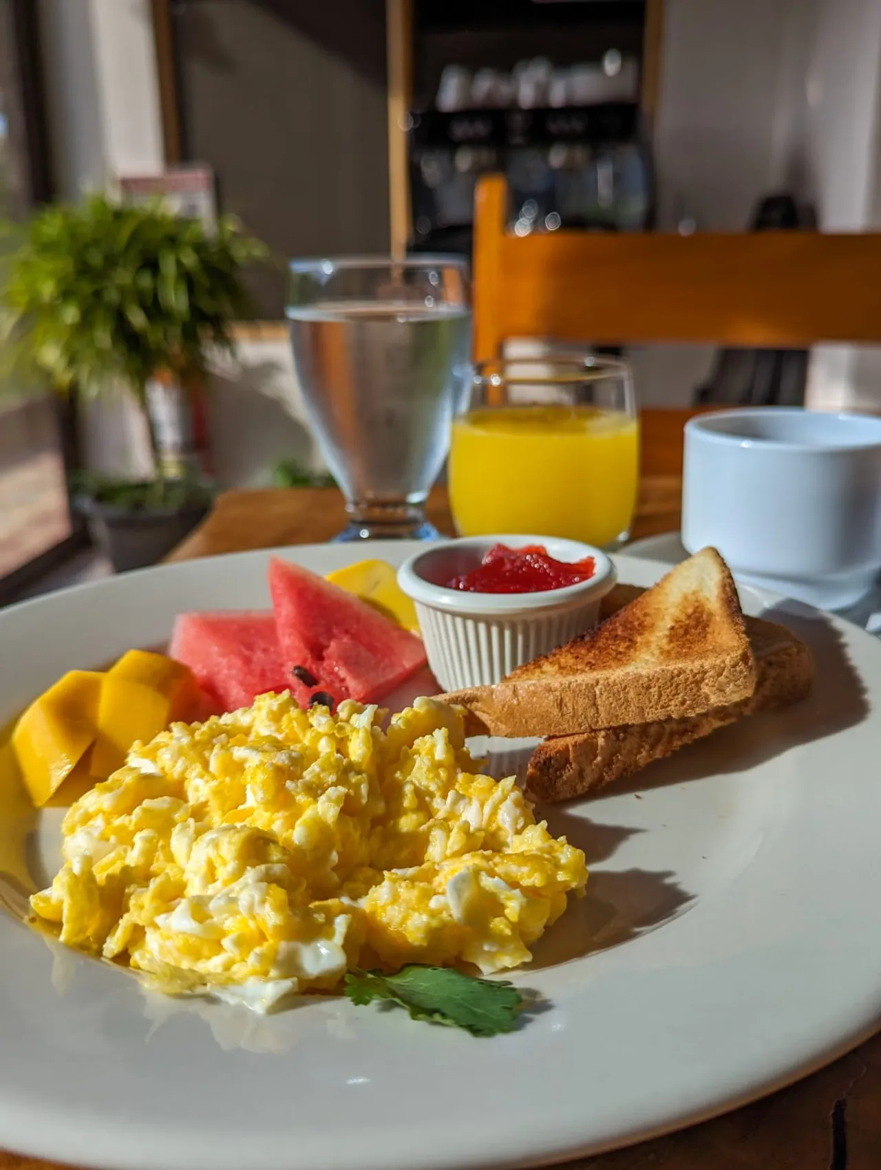 Desayuno con huevos revueltos, tostadas, fruta y jugo de naranja
