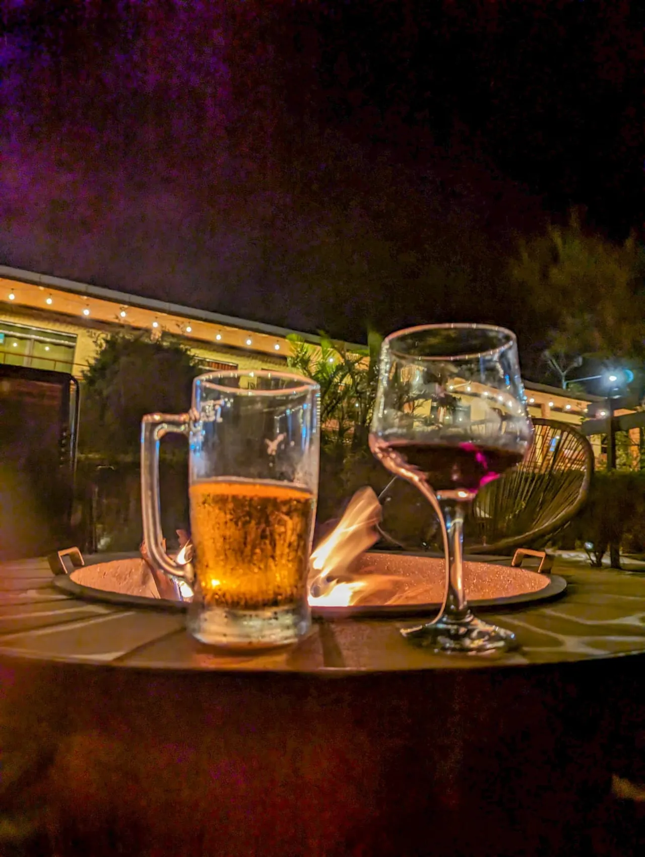 Cerveza y copa de vino junto a la fogata de noche